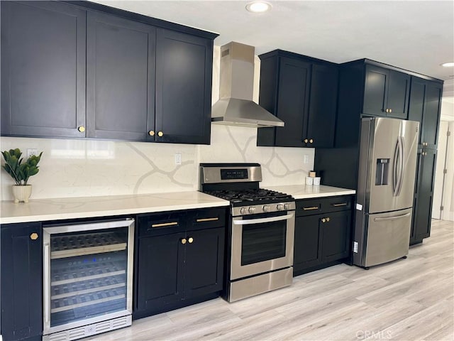 kitchen with wine cooler, light wood-style flooring, stainless steel appliances, wall chimney range hood, and decorative backsplash