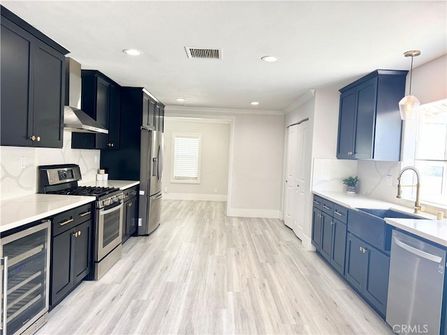 kitchen featuring tasteful backsplash, stainless steel appliances, wine cooler, a sink, and wall chimney exhaust hood
