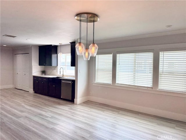 kitchen with light countertops, baseboards, stainless steel dishwasher, a sink, and visible vents