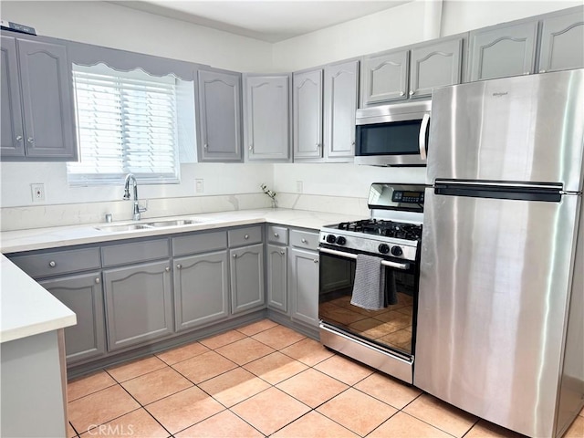 kitchen with light tile patterned flooring, a sink, gray cabinets, and appliances with stainless steel finishes