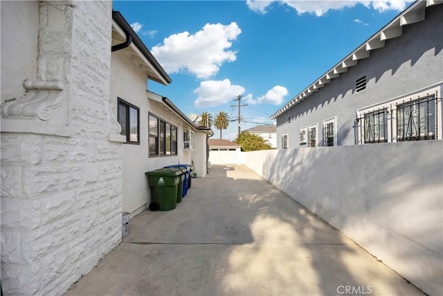 view of home's exterior with stucco siding, fence, and a patio