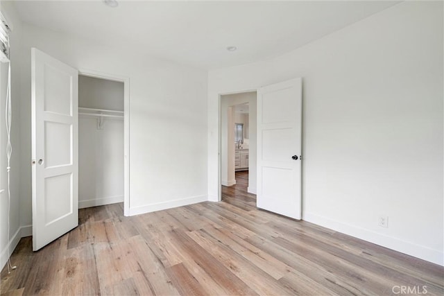 unfurnished bedroom featuring baseboards, light wood-type flooring, and a closet
