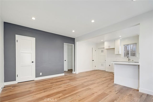 unfurnished living room featuring baseboards, recessed lighting, and light wood-style floors