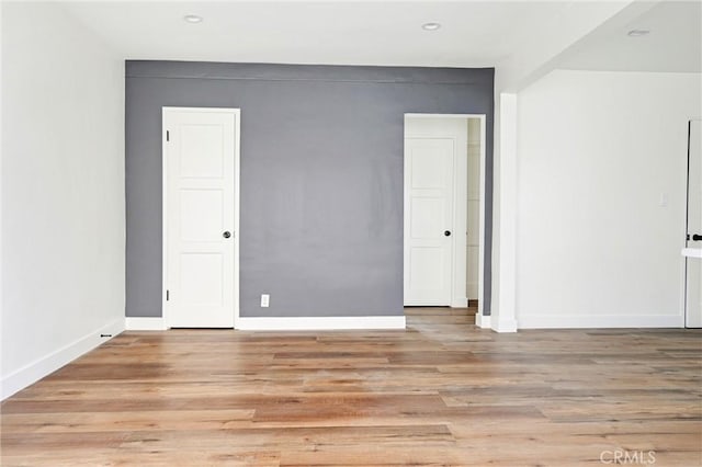empty room with baseboards, light wood finished floors, and recessed lighting