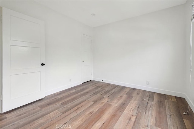 unfurnished room featuring baseboards and light wood-type flooring