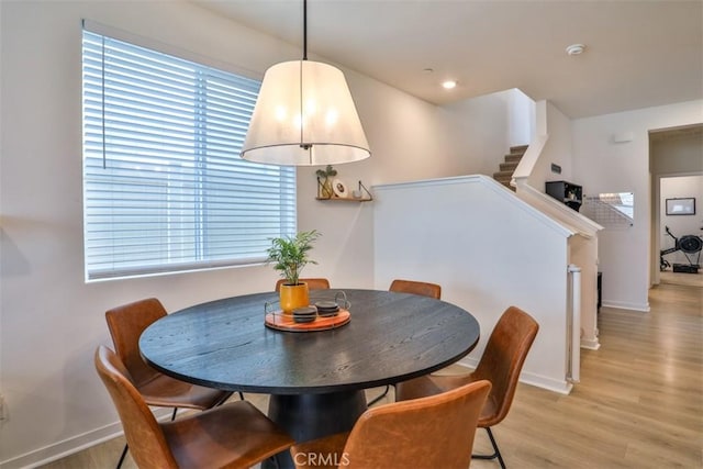 dining area with baseboards, stairway, and light wood-type flooring