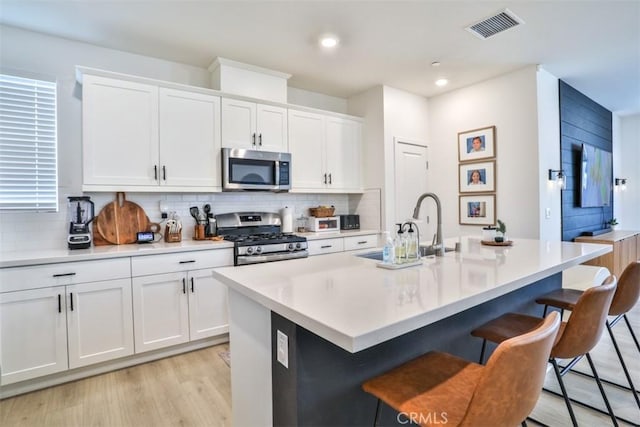 kitchen with a breakfast bar, visible vents, backsplash, and appliances with stainless steel finishes