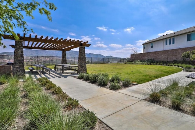 view of community with a lawn, fence, a pergola, and a mountain view