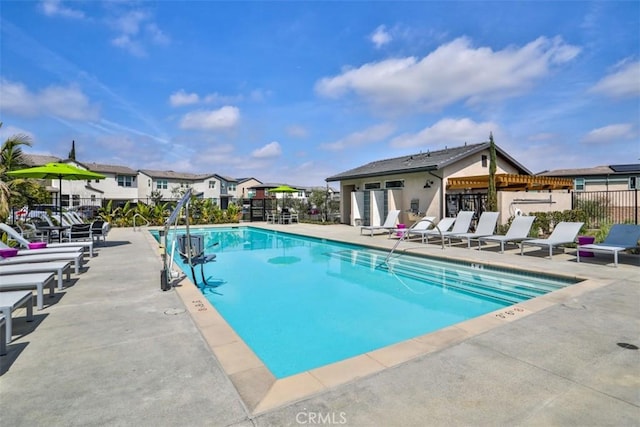 community pool featuring a residential view, a patio, and fence