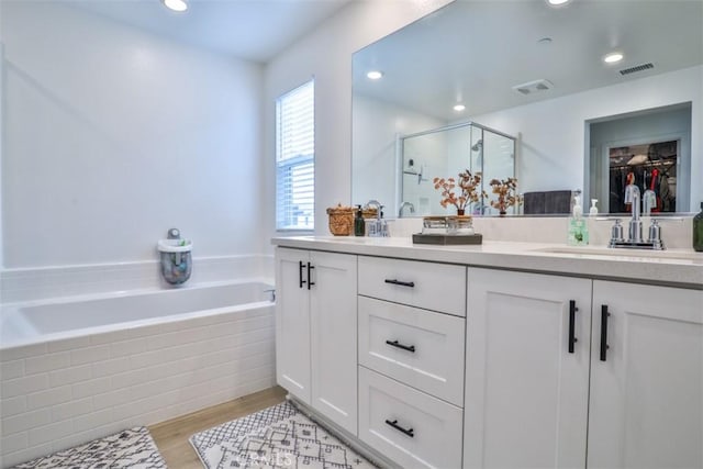 24307 Juni Ct, Corona, CA 92883 - bathroom featuring a stall shower, double vanity, a garden tub, wood finished floors, and a spacious closet