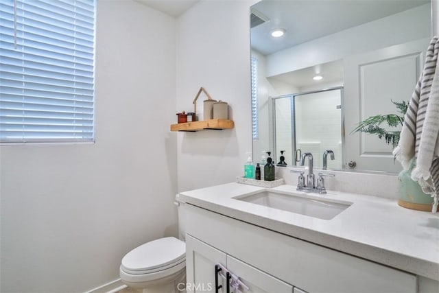 full bathroom featuring vanity, toilet, a stall shower, baseboards, and plenty of natural light