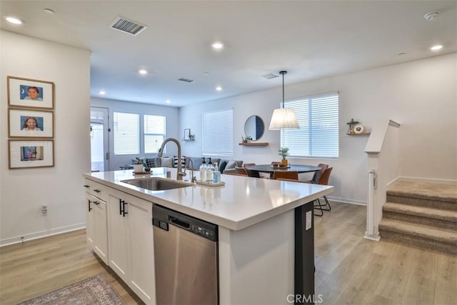 kitchen featuring stainless steel dishwasher, a sink, visible vents, light wood finished floors, and a kitchen island with sink