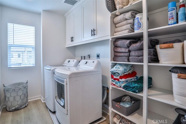 laundry room with plenty of natural light, washer and dryer, cabinet space, light wood-type flooring, and visible vents