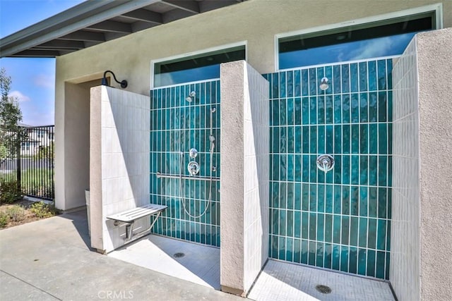 full bathroom featuring a walk in shower, a textured wall, and concrete floors