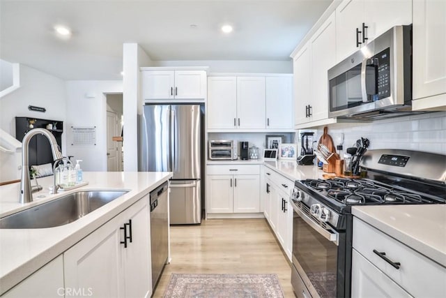 24307 Juni Ct, Corona, CA 92883 - kitchen with appliances with stainless steel finishes, a sink, white cabinetry, light wood-style flooring, and recessed lighting