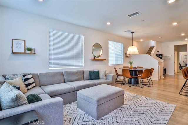 living area featuring visible vents, recessed lighting, light wood-style flooring, and stairs