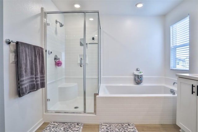 bathroom with recessed lighting, a stall shower, and a garden tub