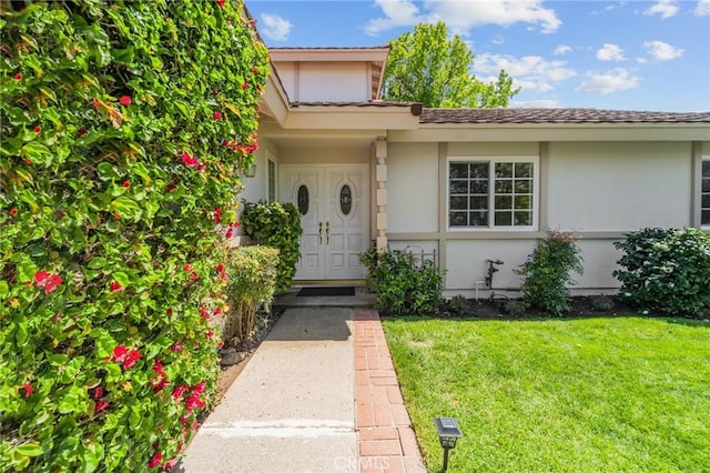 doorway to property with a lawn and stucco siding