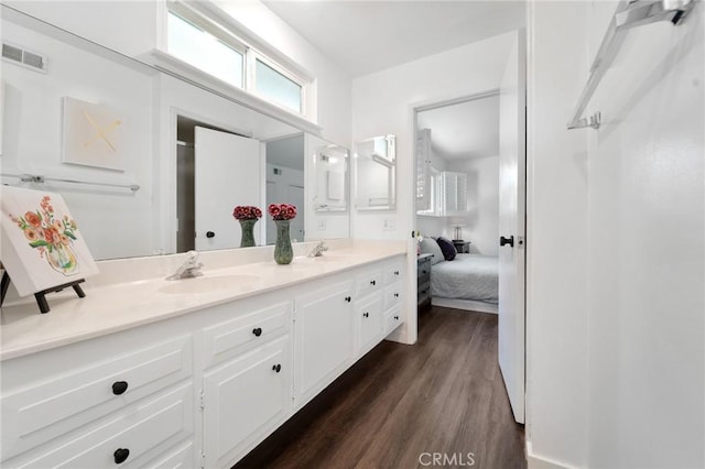 full bath with double vanity, visible vents, a sink, and wood finished floors