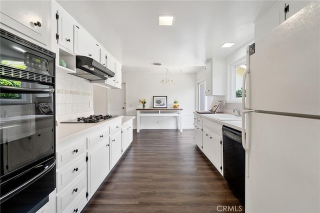 kitchen with backsplash, a sink, light countertops, black appliances, and a warming drawer