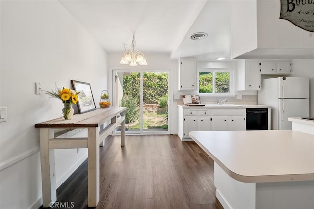 kitchen with light countertops, a chandelier, black dishwasher, freestanding refrigerator, and dark wood-style floors