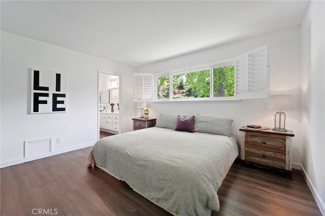 bedroom with baseboards, wood finished floors, and connected bathroom