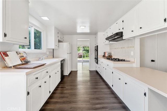 kitchen with gas cooktop, a sink, black oven, tasteful backsplash, and under cabinet range hood