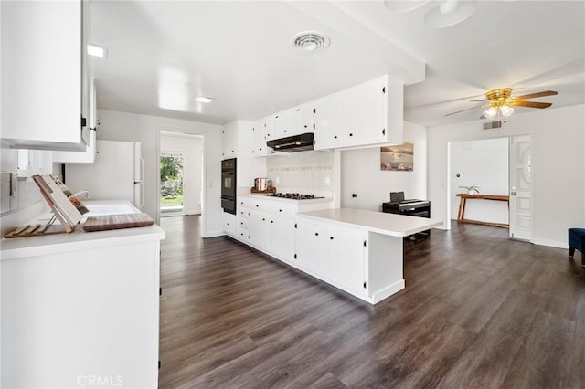 kitchen featuring dark wood finished floors, light countertops, a sink, freestanding refrigerator, and black oven