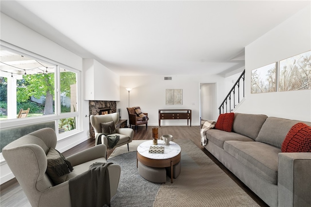 living area with visible vents, wood finished floors, stairway, and a fireplace