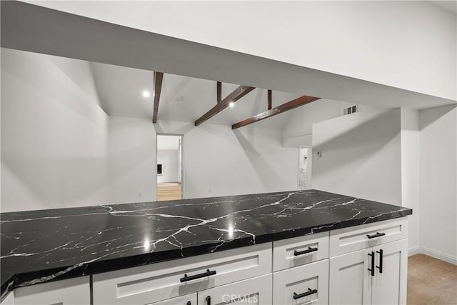 23817 Crest Forest Dr, Crestline, CA 92325 - kitchen with visible vents, beam ceiling, white cabinetry, dark stone countertops, and light wood-style flooring