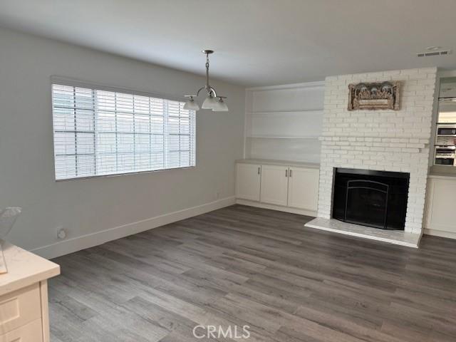 13305 Cordary Ave, Hawthorne, CA 90250 - unfurnished living room featuring wood finished floors, a brick fireplace, and a chandelier
