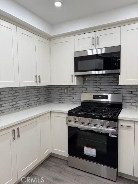 13305 Cordary Ave, Hawthorne, CA 90250 - kitchen featuring appliances with stainless steel finishes, white cabinets, light wood-style floors, tasteful backsplash, and recessed lighting
