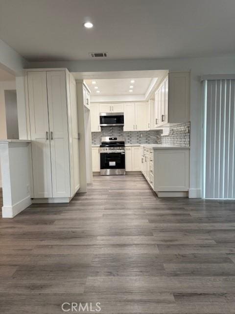 13305 Cordary Ave, Hawthorne, CA 90250 - kitchen featuring stainless steel appliances, recessed lighting, dark wood-style flooring, tasteful backsplash, and white cabinetry