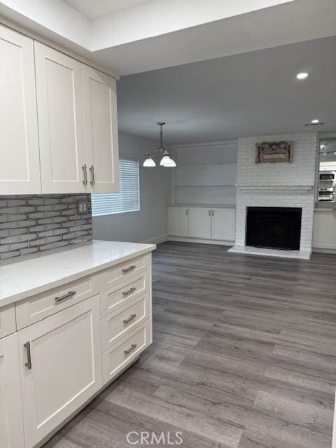 13305 Cordary Ave, Hawthorne, CA 90250 - kitchen with white cabinets, open floor plan, a chandelier, wood finished floors, and decorative backsplash