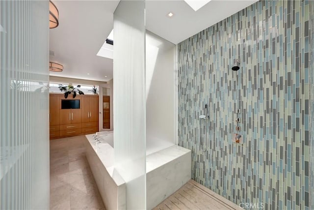 full bath with a tile shower, a garden tub, and a skylight