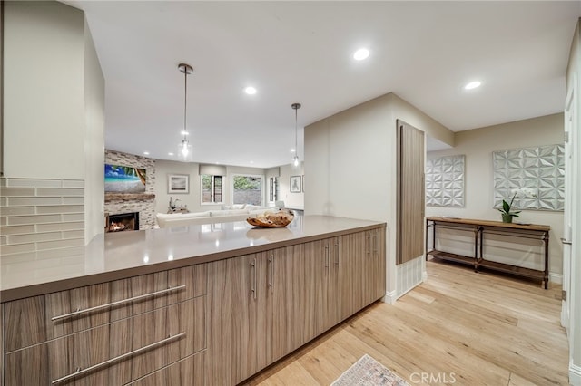 247 Calliope St, Laguna Beach, CA 92651 - kitchen featuring open floor plan, light wood-style floors, a brick fireplace, hanging light fixtures, and light countertops