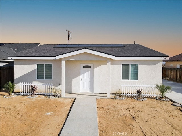 view of front facade featuring stucco siding, a shingled roof, and fence