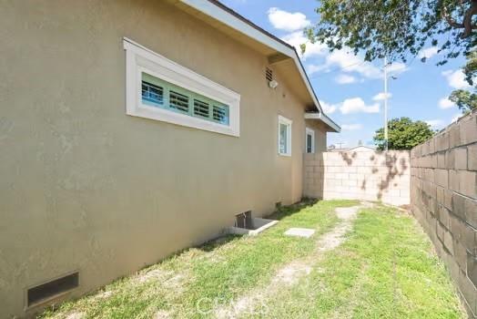 view of property exterior with stucco siding, fence, and a yard