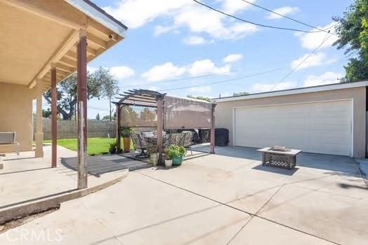 view of patio featuring a detached garage, fence, an outdoor structure, and a pergola