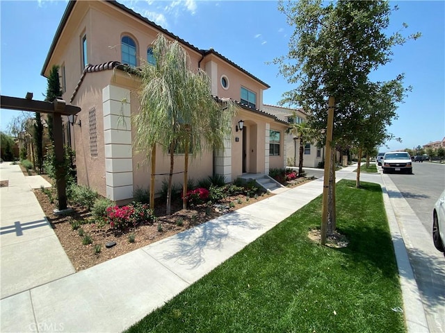 mediterranean / spanish home with a front yard, stucco siding, and a tiled roof