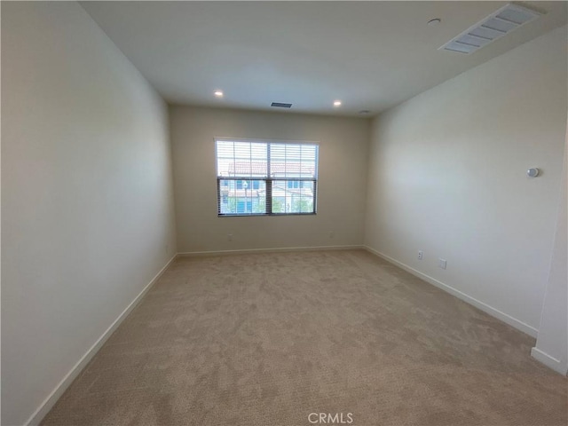 spare room with light colored carpet, visible vents, and baseboards