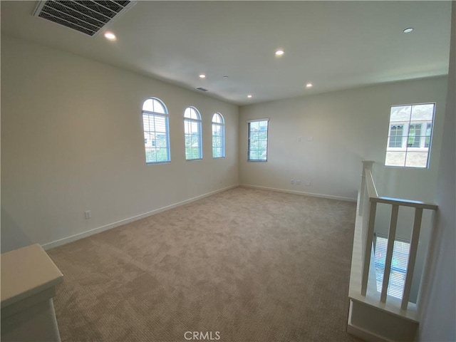 carpeted empty room featuring baseboards, visible vents, and recessed lighting