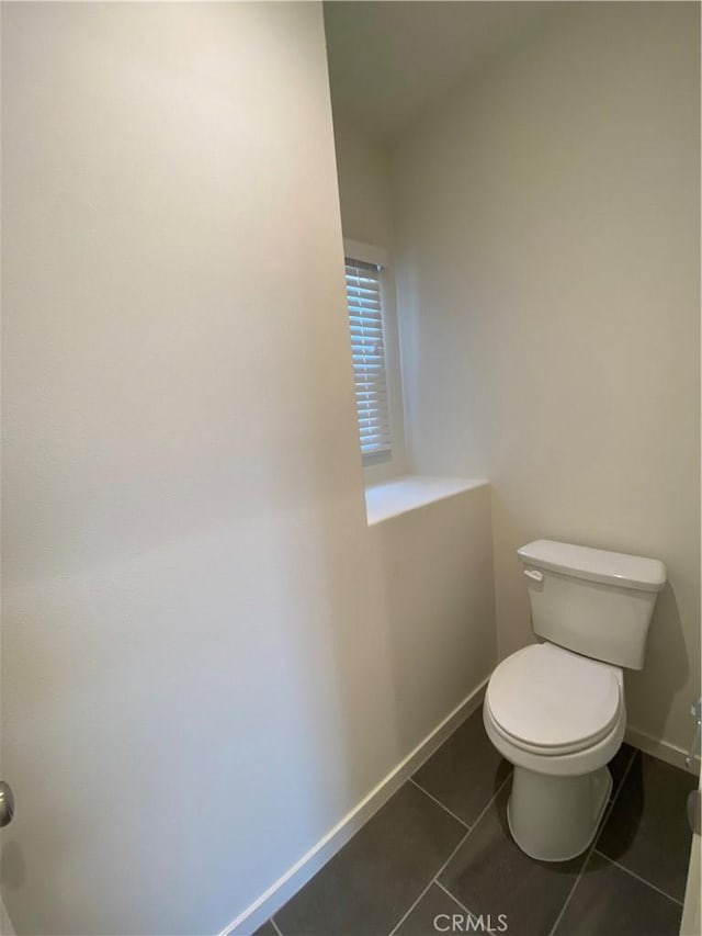 bathroom with baseboards, toilet, and tile patterned flooring