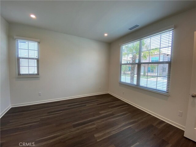 empty room featuring recessed lighting, dark wood-style floors, baseboards, and a wealth of natural light