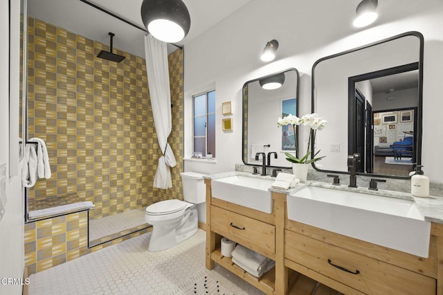 full bathroom featuring double vanity, tiled shower, and a sink