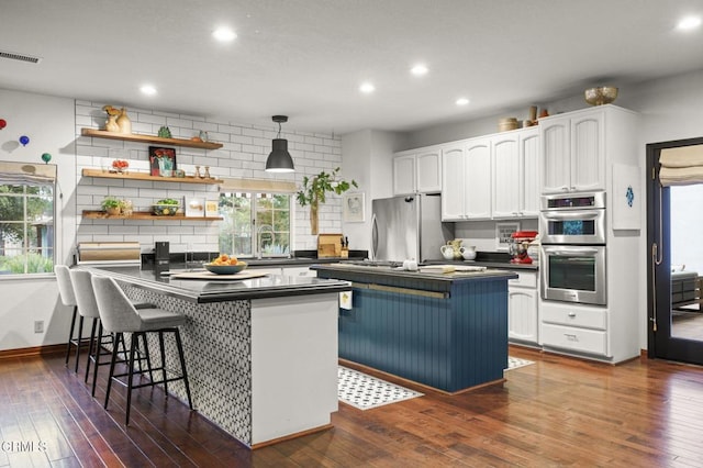 kitchen featuring stainless steel appliances, dark countertops, visible vents, a sink, and white cabinetry