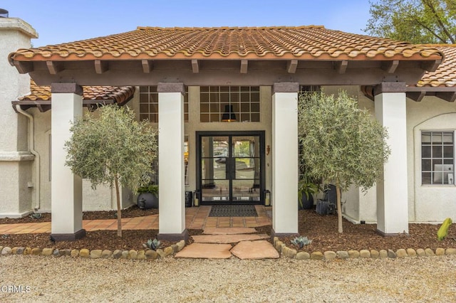 view of exterior entry featuring stucco siding and a tile roof