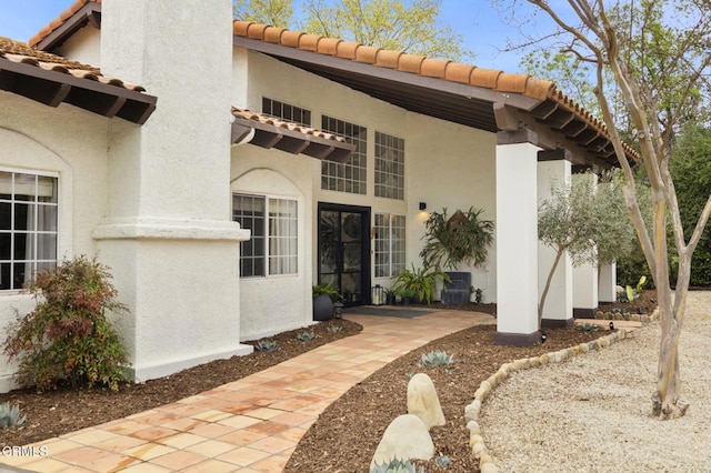 property entrance with a tiled roof and stucco siding