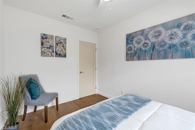 bedroom with a ceiling fan, baseboards, visible vents, and wood finished floors