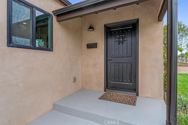 doorway to property featuring stucco siding